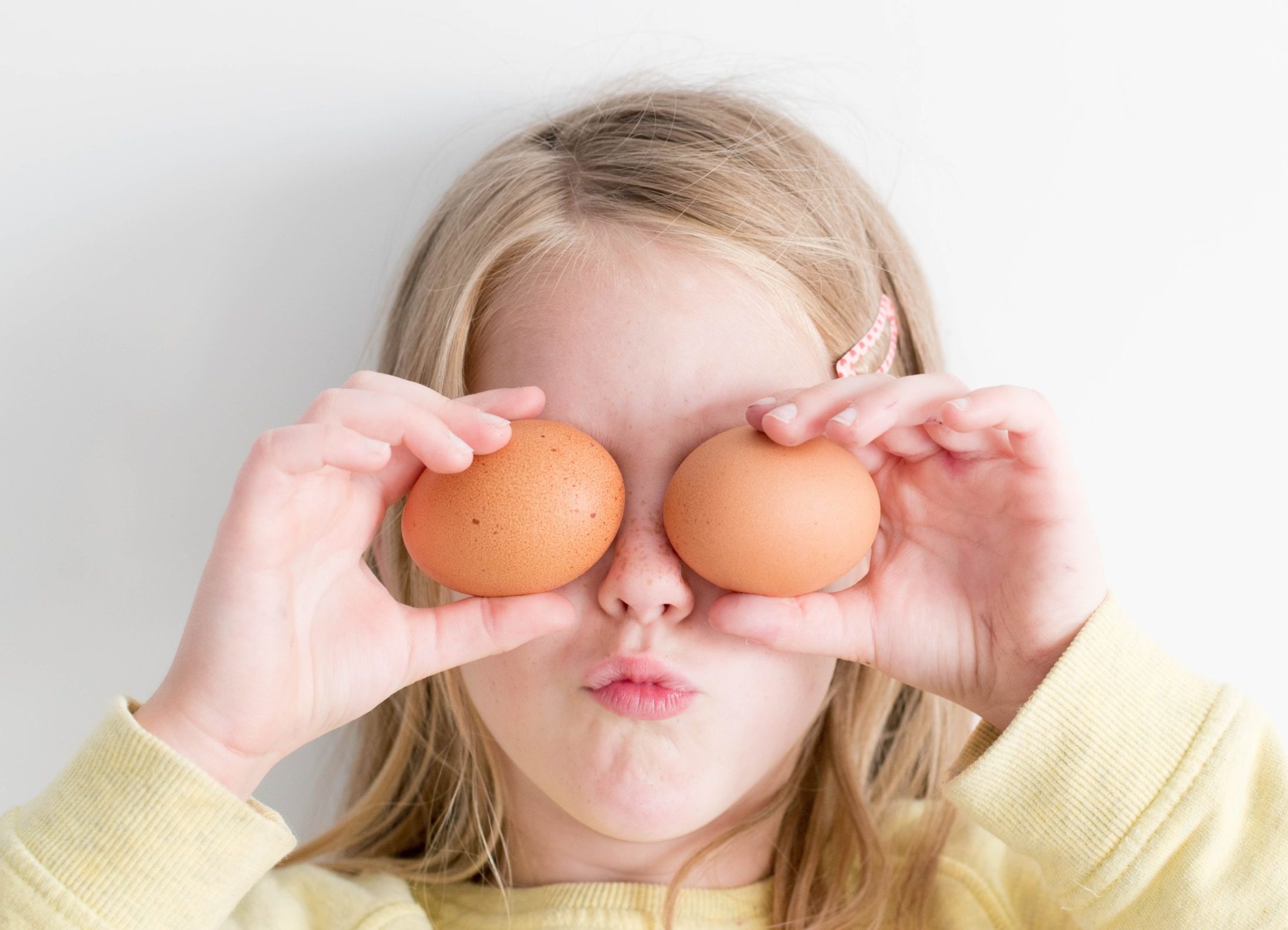 Young girl holding eggs in fron of her eyes